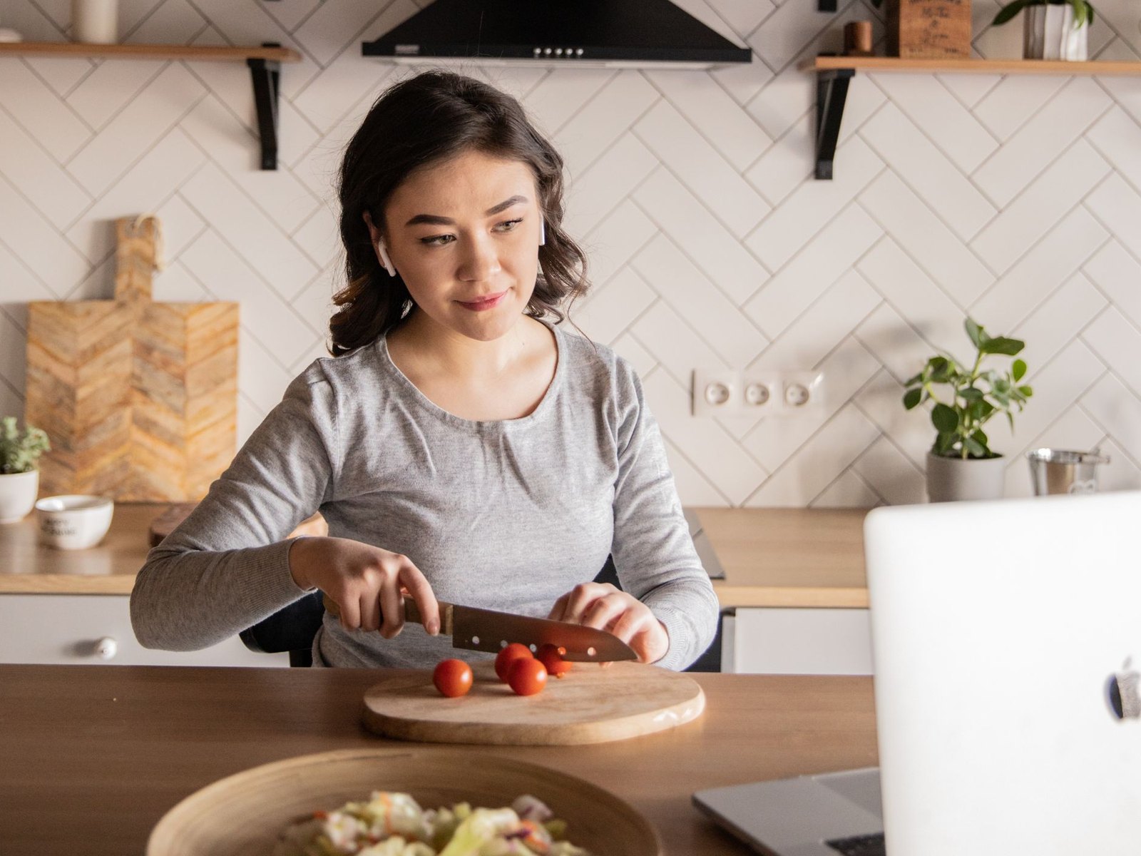 Someone cooking at home, following along on a laptop propped on the kitchen counter